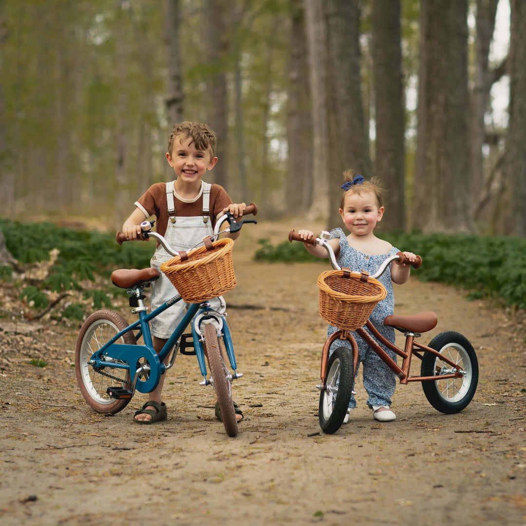 Two children with bicycles on a forest path.