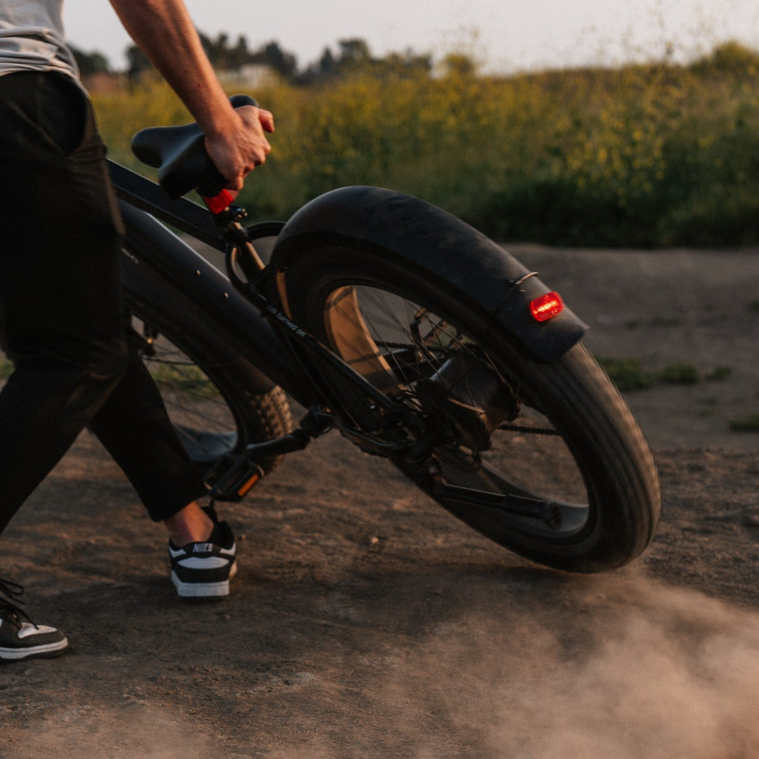Rider on a fat tire electric bike navigating a dirt trail through the woods.