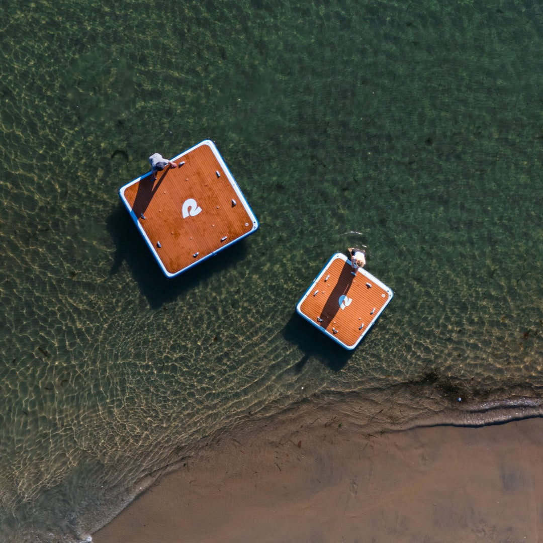 An aerial view of two inflatable docks in the water beside the shore.
