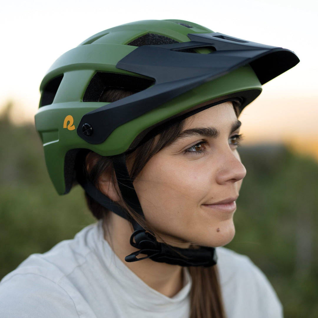 A woman wearing a green Rowan Mountain Bike Helmet outdoors.
