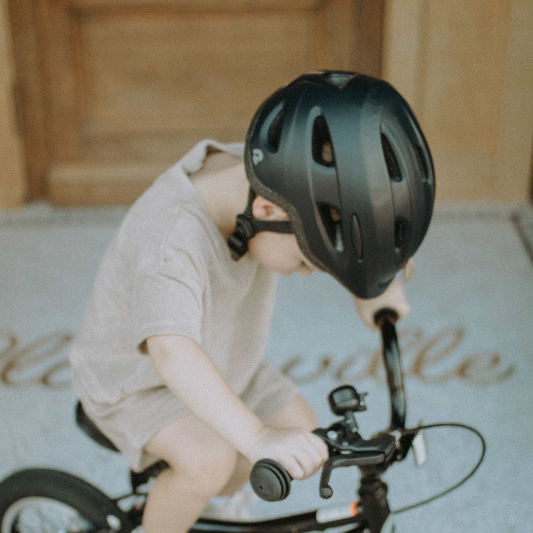 Child wearing a properly fitted bike helmet while riding a bike outdoors.