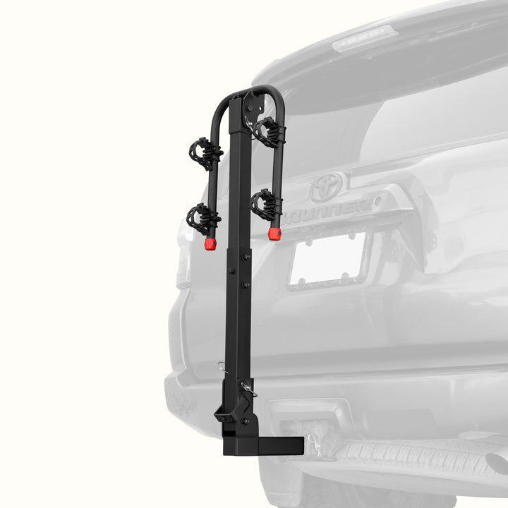 retrospec Lenox Hitch Mount Car Bike Rack (2-Bikes)
installed on the rear of a Toyota 4Runner, shown empty in the folded upright position with cradle arms raised and red safety caps in place.