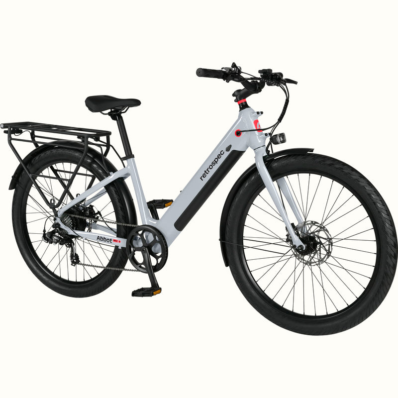 A modern, sleek Abbot Rev 2 Step Through electric bike in gray with a low step-through frame, wide tires, and a rear rack, branded "retrospec."