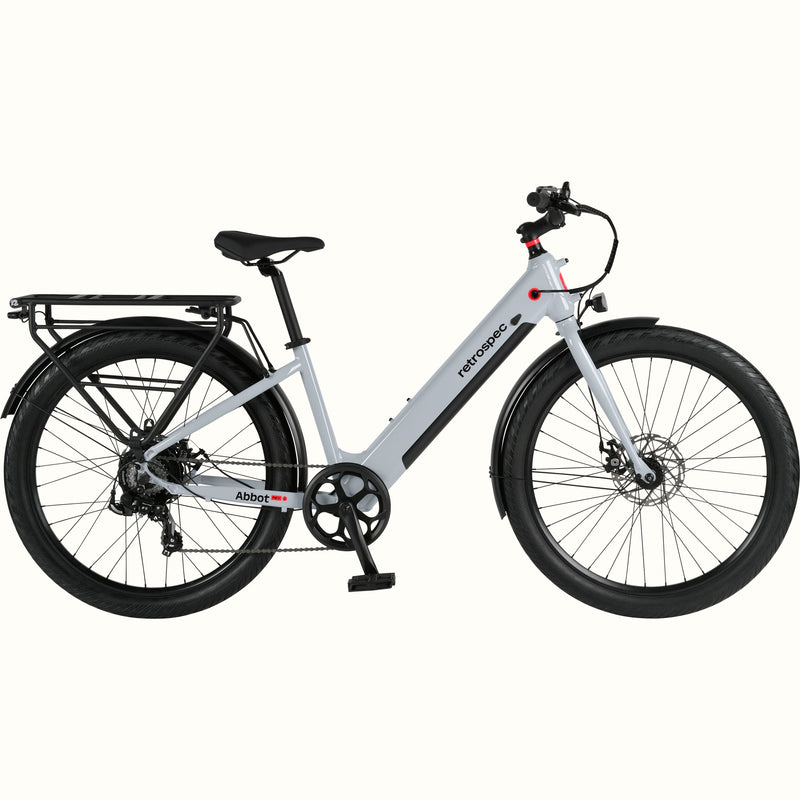 A modern, sleek Abbot Rev 2 Step Through electric bike in gray with a low step-through frame, wide tires, and a rear rack, branded "retrospec."