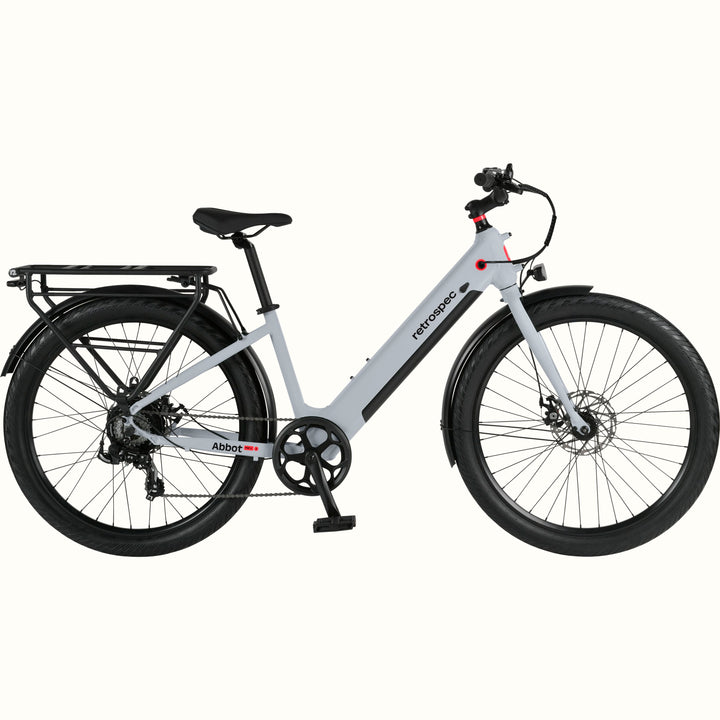 A modern, sleek Abbot Rev 2 Step Through electric bike in gray with a low step-through frame, wide tires, and a rear rack, branded "retrospec."