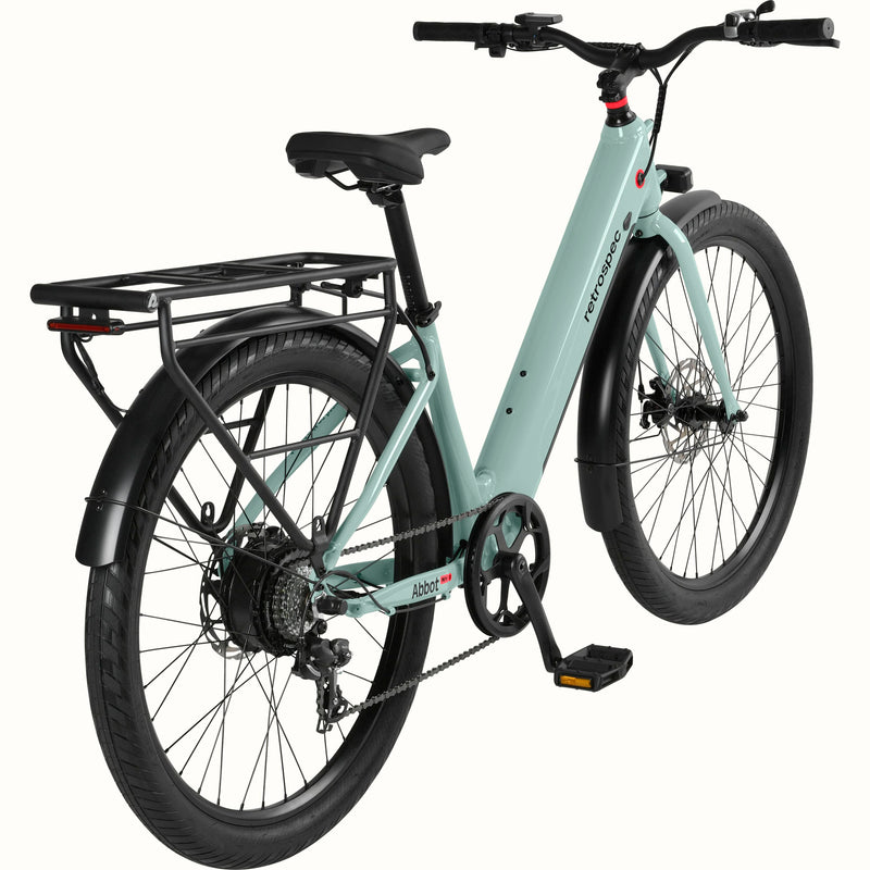 A modern, sleek Abbot Rev 2 Step Through electric bike in light greenish blue with a low step-through frame, wide tires, and a rear rack, branded "retrospec."