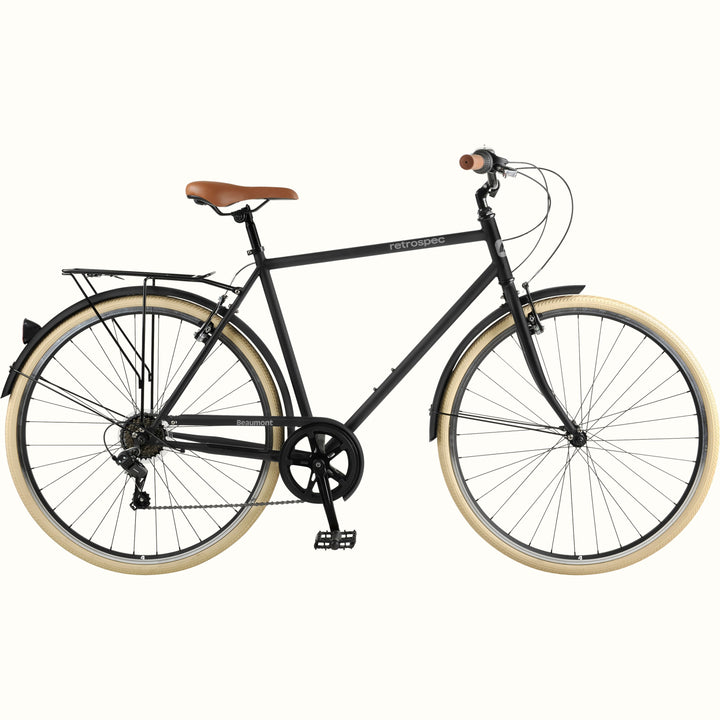 A black bicycle with cream-colored tires, a brown leather saddle, and brown handlebar grips, shown against a solid off-white background.
