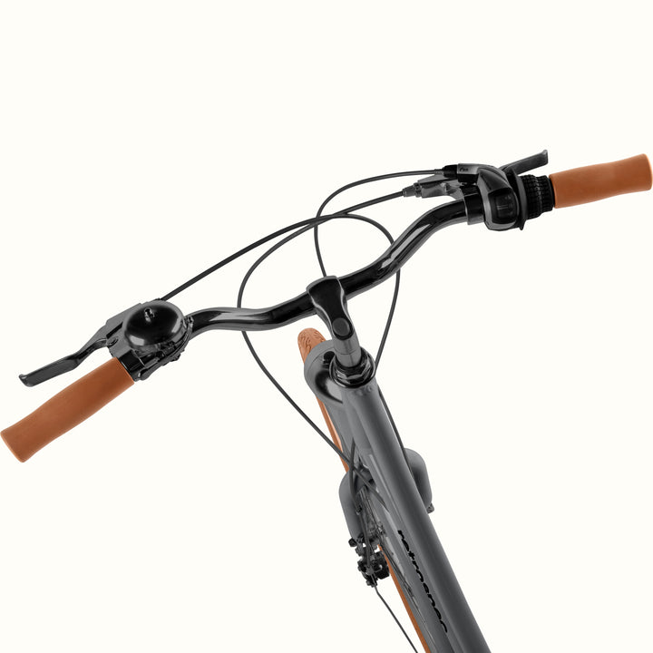 Handlebar detail on the retrospec Beaumont Plus with an 8 speed twist shifter, bell, and brown grips.