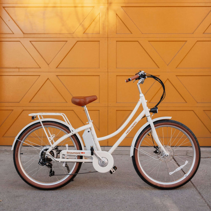 White Beaumont Rev 3 City Electric Bike - Step Through with brown seat against a yellow geometric-patterned garage door.