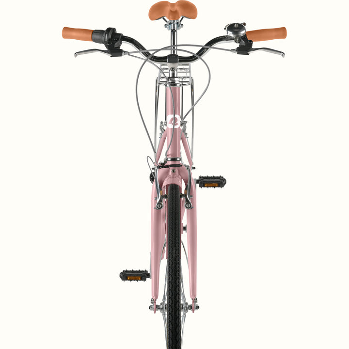 Front view of retrospec Beaumont ST urban bike in dusty rose showing handlebar bell, brown leather grips, front rack, and pedals.