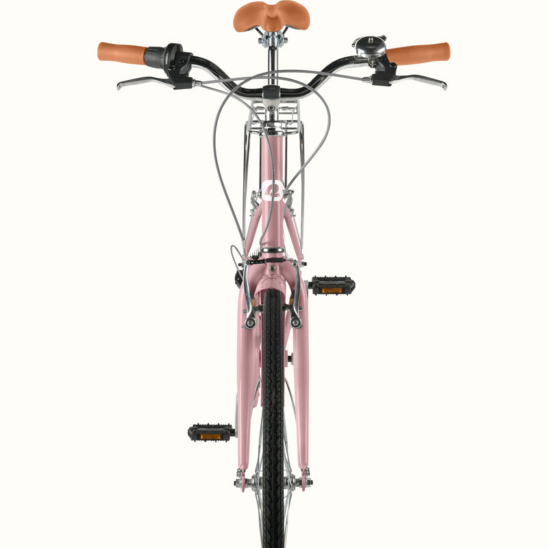 Front view of retrospec Beaumont ST urban bike in dusty rose showing handlebar bell, brown leather grips, front rack, and pedals.