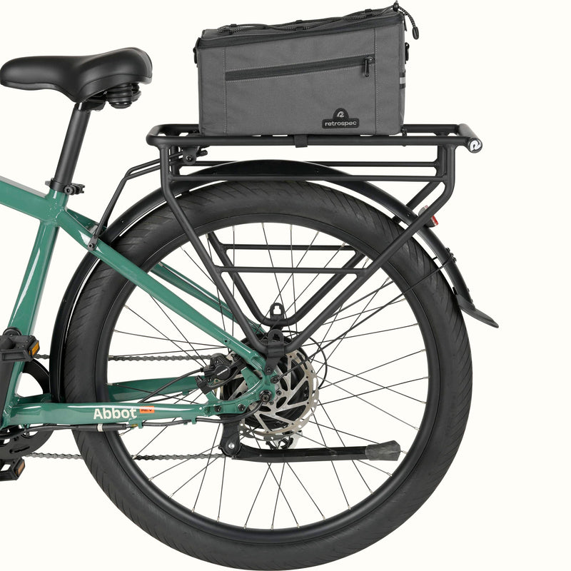 Side view of a green electric bike with a black cargo rack and the Cahoot Rear Rack Trunk Bag attached.