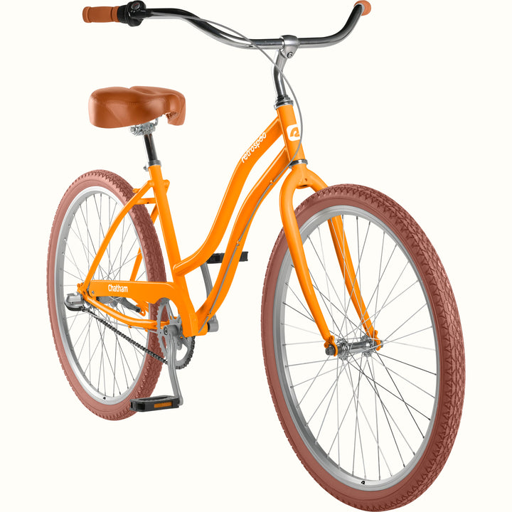 retrospec Chatham women's cruiser bike showing the step-through orange frame, chain, and pedals from a 3/4 angle.