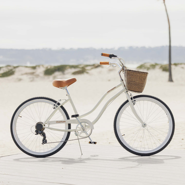 retrospec Chatham beach cruiser bike with wicker basket parked on a boardwalk near sand dunes.