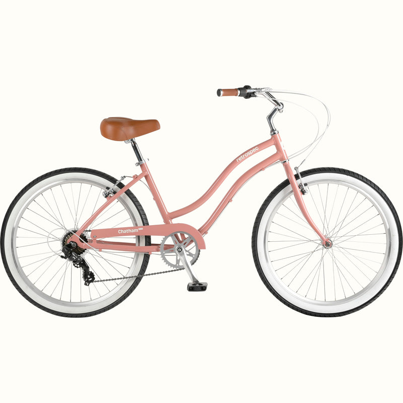 A pink beach cruiser bicycle with a brown seat and white-walled tires against a white background.