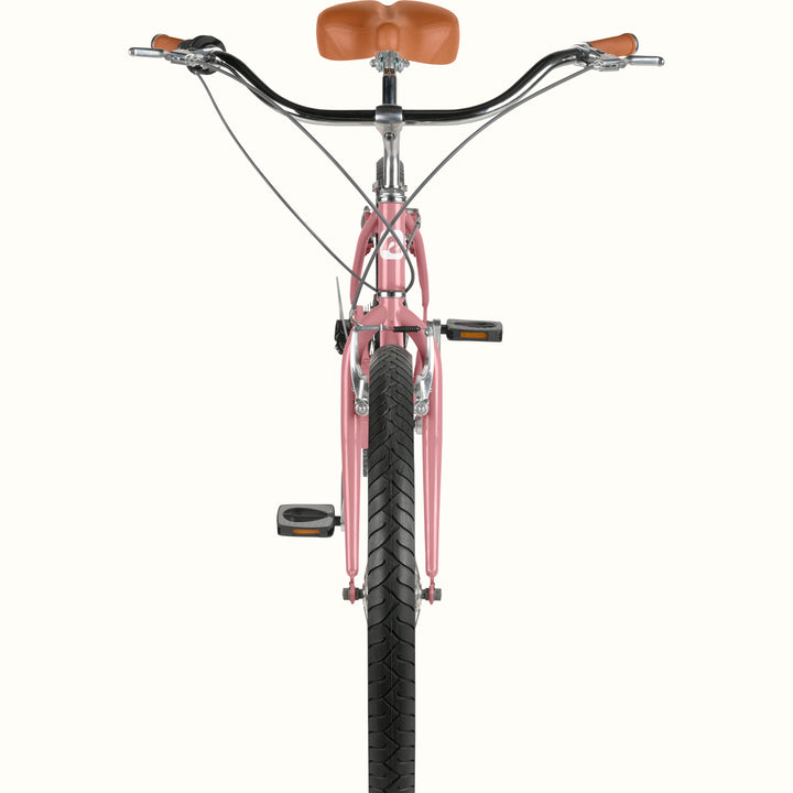 Front-facing close-up of retrospec Chatham Plus cruiser bike for women in dusty rose showing wide handlebars, brake levers, brown grips, and black tread tire.