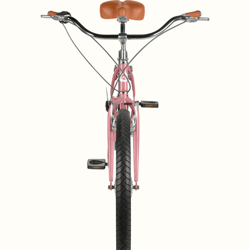 Front-facing close-up of retrospec Chatham Plus cruiser bike for women in dusty rose showing wide handlebars, brake levers, brown grips, and black tread tire.