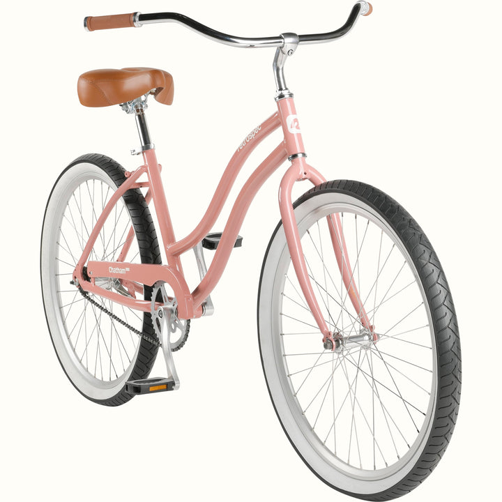 A pink cruiser bicycle with white-wall tires and a brown saddle and grips.