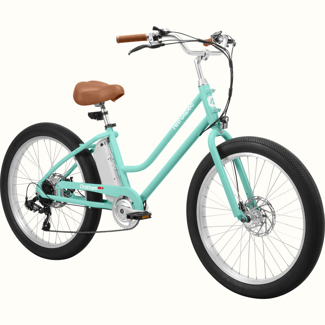 A seafoam Chatham Rev 3 Beach Cruiser Electric Bike - Step Through with a brown seat, wide tires, and a sleek design, ideal for casual riding.