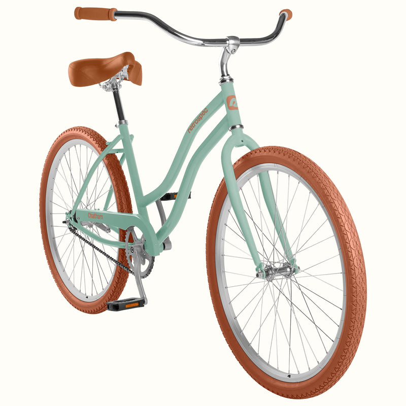 A matcha green step-through bicycle with brown leather saddle and handlebar grips, brown textured tires, and silver chrome components, shown on a solid off-white background.