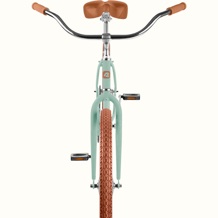 Front view of a cruiser bicycle with a matcha green frame, brown saddle and handlebar grips, and a brown knobby tire, shown on a solid off-white background.