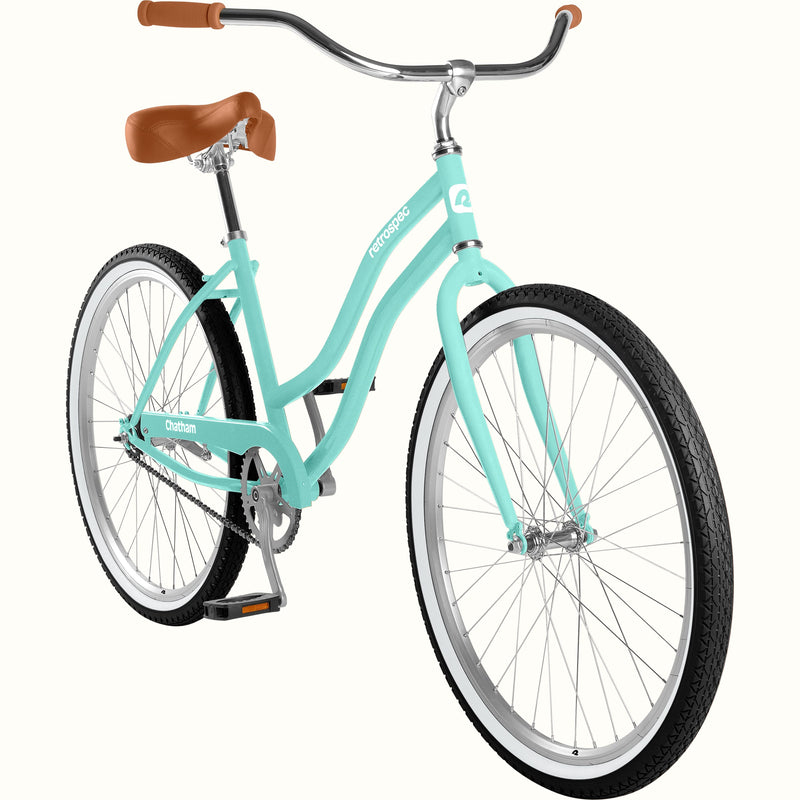 A step-through cruiser bicycle in seafoam with brown leather saddle and grips, silver handlebars, and black tires with white sidewalls, shown on a plain white background.