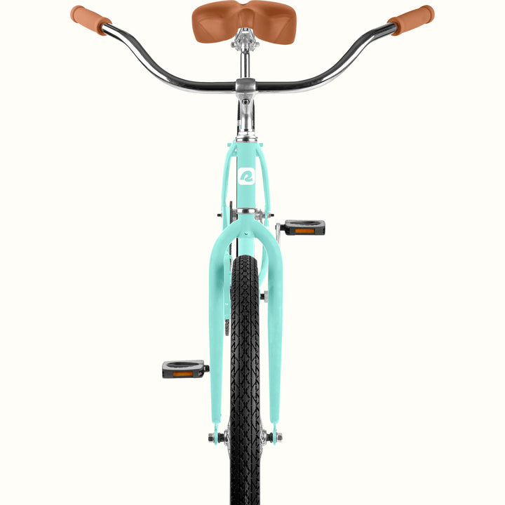 Front view of a cruiser-style bicycle with a seafoam frame, brown saddle and handlebar grips, and black tires on a plain off-white background.