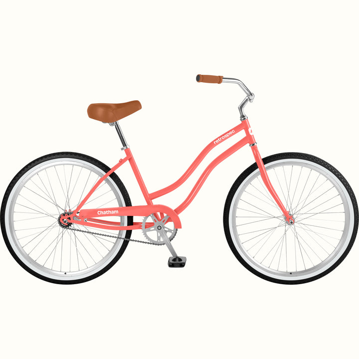 A coral pink step-through bicycle with brown leather saddle and handle grips, white rims, and black tires, shown from a side profile on a light cream background. The model name 'Chatham' is visible on the frame.