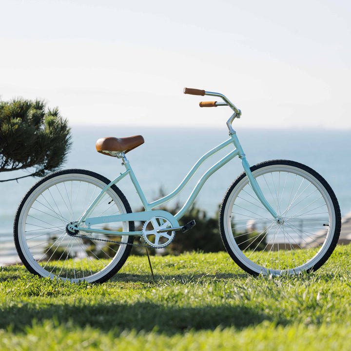 A light blue cruiser bicycle parked on grass with a scenic ocean backdrop.