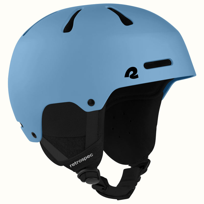 A matte  blue ski helmet with black ventilation slots, a black interior lining, and a black adjustable chin strap. The brand name 'retrospec' is printed in white on the strap, and a stylized 'r' logo is visible on the side.