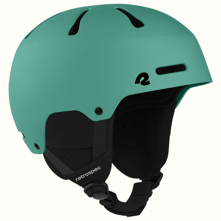 A matte mint green ski helmet with black ventilation slots, a black interior padding, and a black adjustable chin strap. The brand name 'retrospec' is printed in white on the strap, and a stylized 'R' logo is on the side.