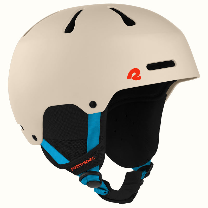 A matte cream-colored ski helmet with black chin straps and bright blue accents, featuring a red retro logo on the side. The brand 'retrospec' is visible on the strap.