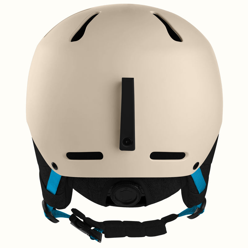 A matte cream-colored ski helmet shown from the back, featuring black ventilation slots, a central vertical vent, and black adjustable chin straps with bright blue accents.