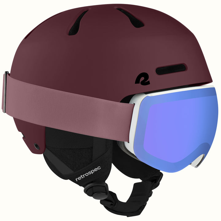 retrospec Comstock ski helmet with goggles in matte dark burgundy, blue mirrored lens goggles clipped to the strap.