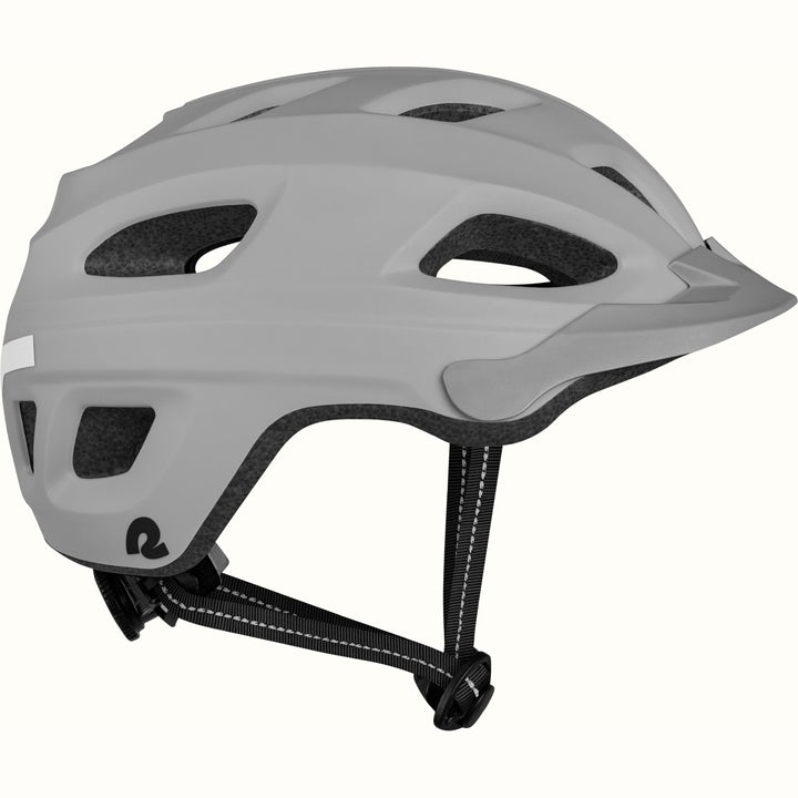 Side view of a Lennon Commuter Bike Helmet in Matte Stone Gray, showing the ventilation ports, reflective side strip, Retrospec logo, short visor, and adjustable chin strap against a clean background.
