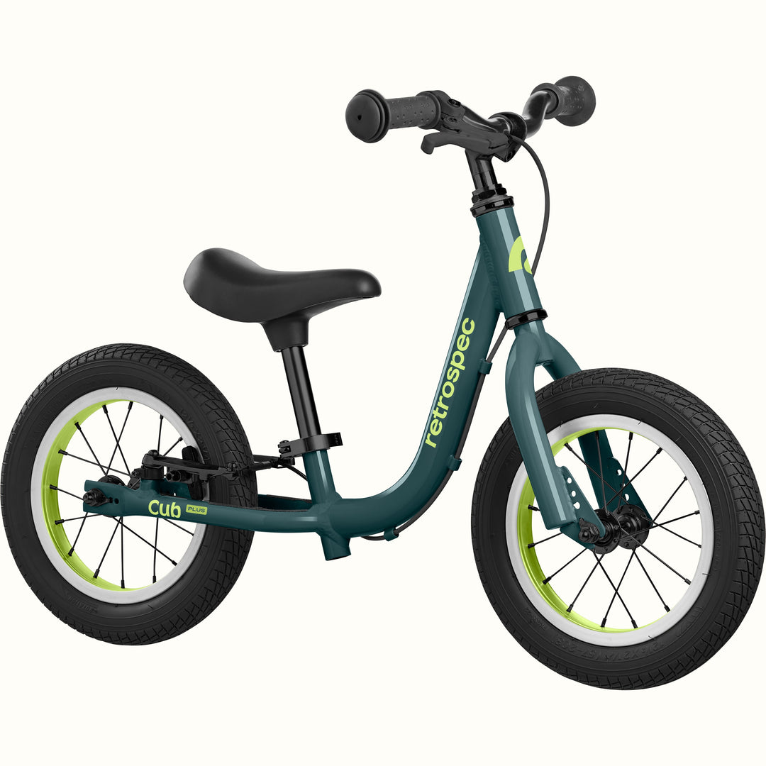 Green balance bike with black seat and wheels on a white background.