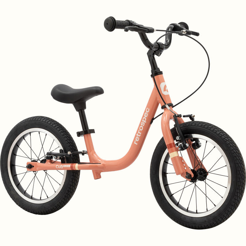 A rose-colored balance bike with black tires and handlebars on a white background.