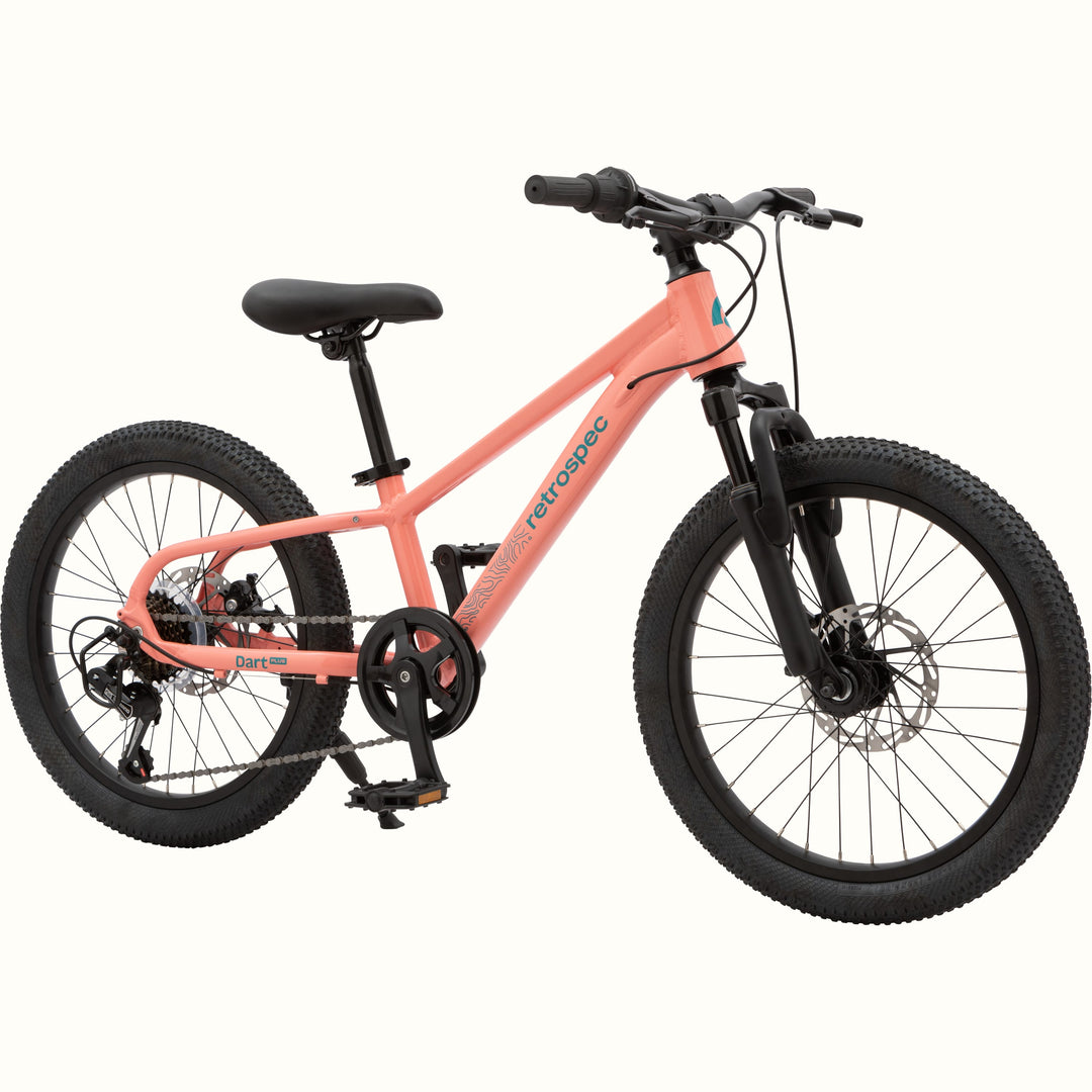Profile view of the Dart Plus 20" Kids' Bike in Fairy Floss Salmon color with blue-gray branded "retrospec" and "Dart Plus" logos on the frame, and thick black tires isolated on a white background.