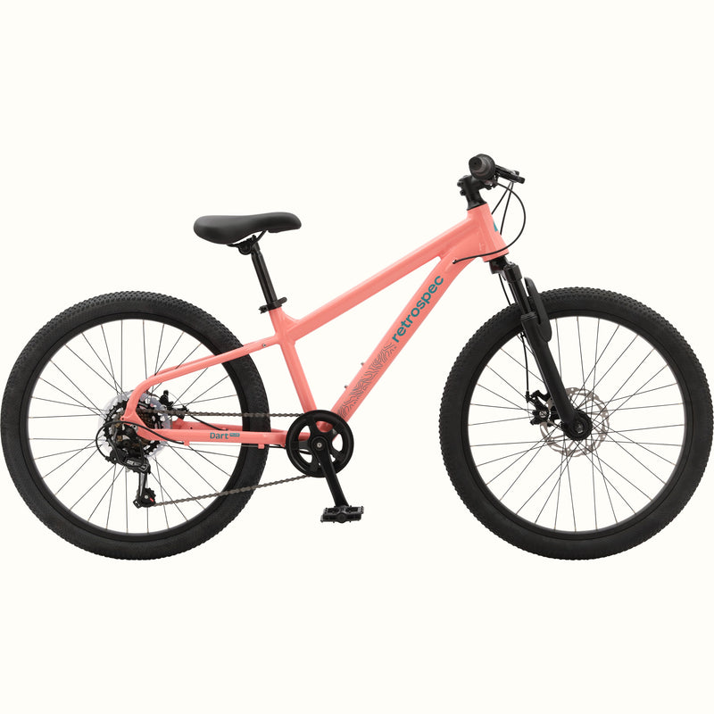 Profile view of the Dart Plus 24" Kids' Bike in Fairy Floss Salmon color with blue-gray branded "retrospec" and "Dart Plus" logos on the frame, and thick black tires isolated on a white background.