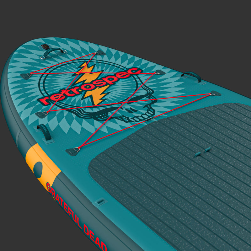 A close up  of the Grateful Dead Weekender Crew XL Multi-Person Inflatable Stand Up Paddle Board 15’ with a "Steal Your Face" design on the nose, and red bungee cord for storage along with a textured surface for grip.