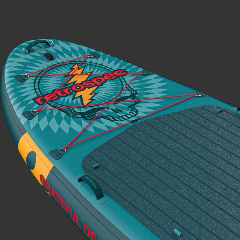 A close up  of the Grateful Dead Weekender Crew Multi-Person Inflatable Stand Up Paddle Board with a "Steal Your Face" design on the nose, and red bungee cord for storage along with a textured surface for grip.