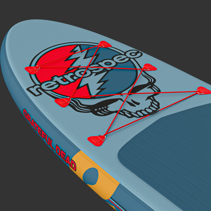 A close-up of the blue Grateful Dead Weekender Inflatable Paddle Board with a "Steal Your Face" or "SYF" graphic, red bungee cords, and the logo "retrospec."