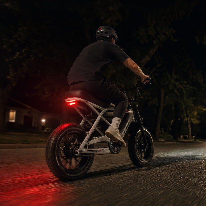 retrospec Valen Rev kids electric bike shown with its glowing rear taillight during a night ride.