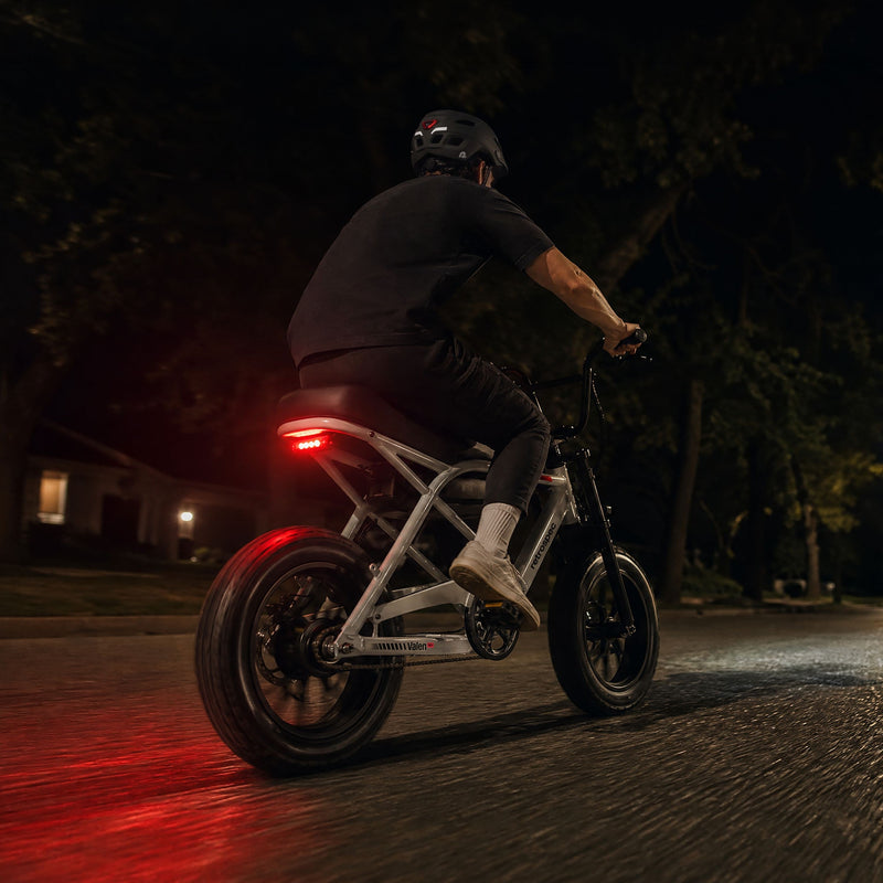 retrospec Valen Rev kids electric bike shown with its glowing rear taillight during a night ride.