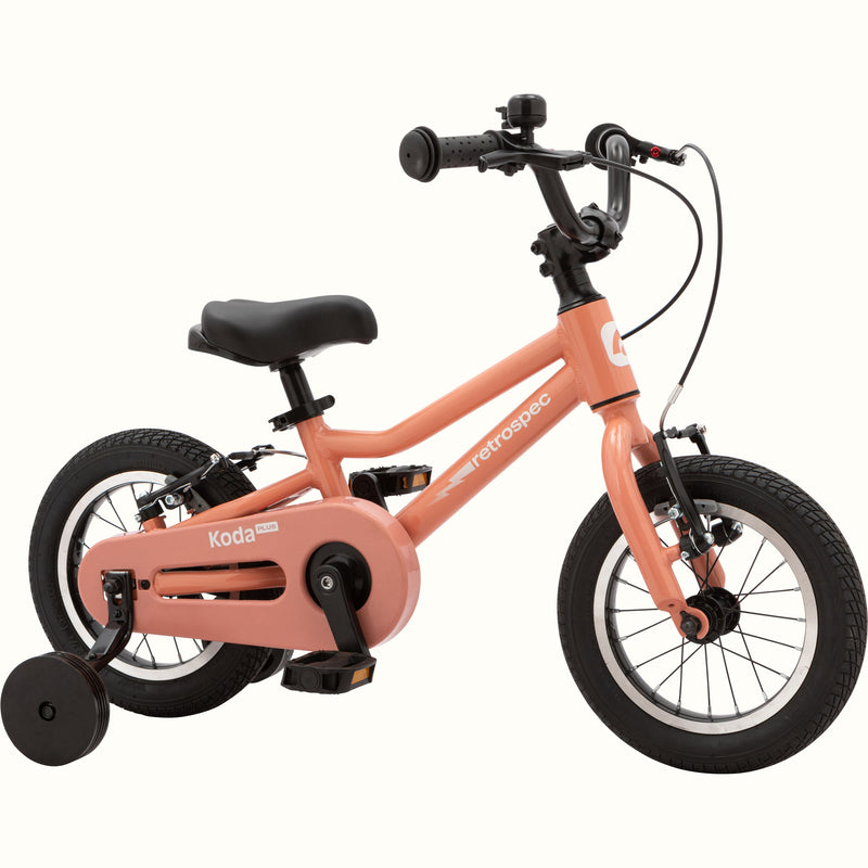 Koda Plus Rose children's bike with training wheels, peach frame, and black details.