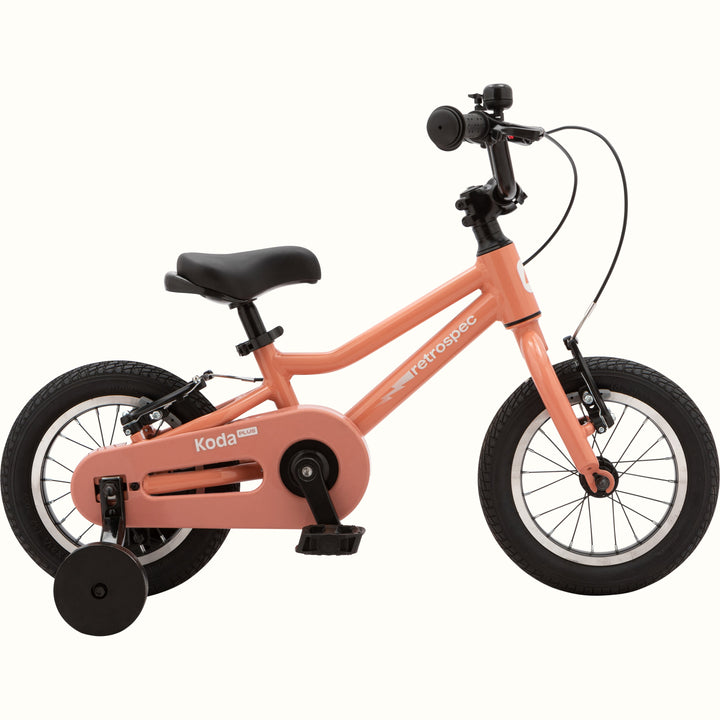 Koda Plus Rose children's bike with training wheels, peach frame, and black details.