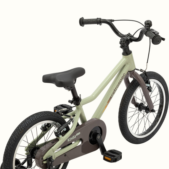 A green and brown kids' Koda Plus 16" bicycle with training wheels, isolated on a white background.