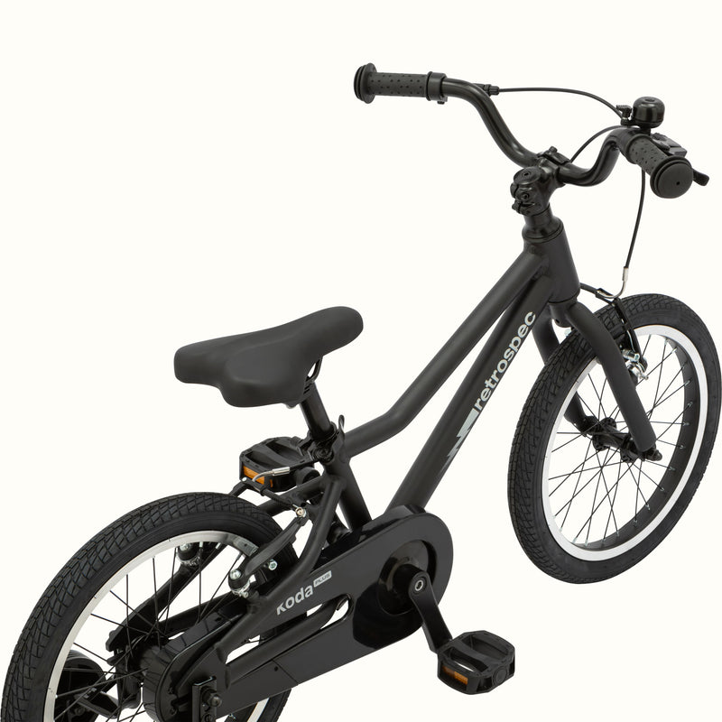 A matte black kids' Koda Plus 16" bicycle with training wheels, isolated on a white background.