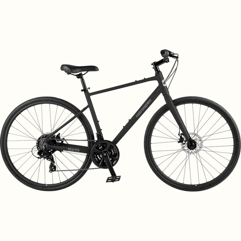 retrospec Martis hybrid bike in Matte Black, side view showing flat handlebar, disc brakes, and triple chainring drivetrain.