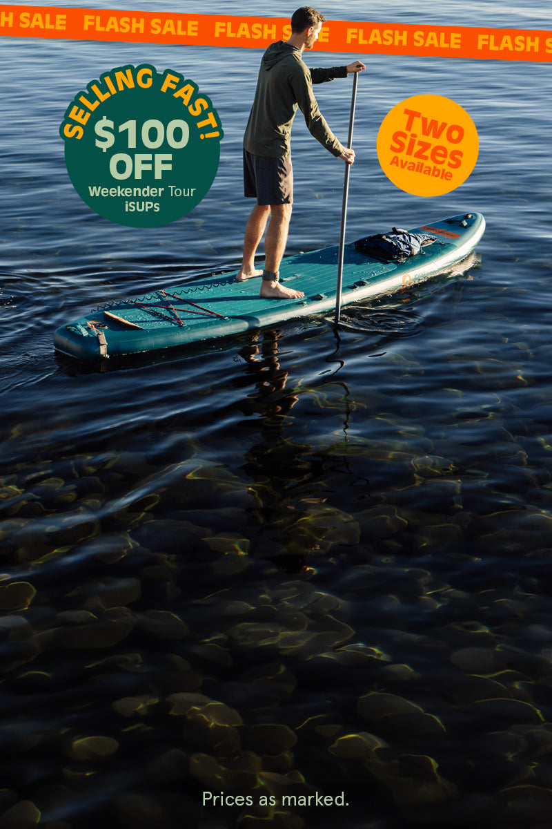 Man paddleboarding on calm water, with promotional text for a flash sale and $100 off Weekender Tour iSUPs.